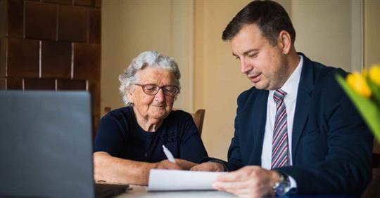 An older woman reviewing documents with a younger man in a suit
