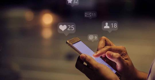 A person holding a phone with floating social media icons around it