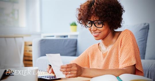 African American woman looking at a piece of paper while using a calculator