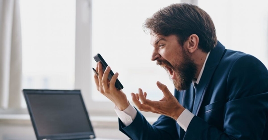 A man angrily screaming at his phone