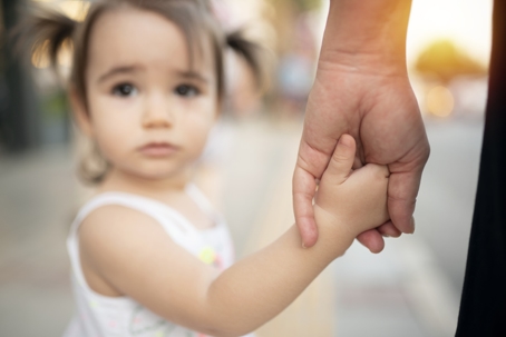 sad child holding parent's hand