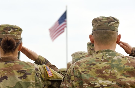Military service members saluting the American flag